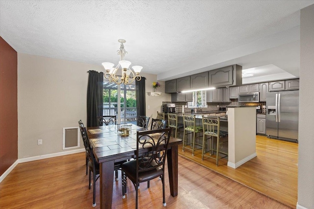 404 E Carriage Ct, Spokane, WA 99218 - dining area with a chandelier, light wood-type flooring, and a textured ceiling
