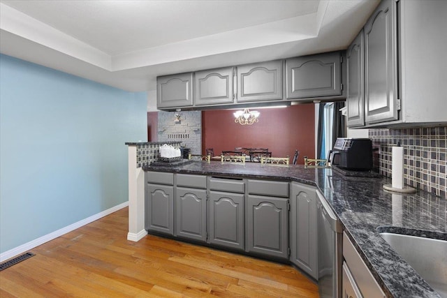 404 E Carriage Ct, Spokane, WA 99218 - kitchen featuring gray cabinetry, decorative backsplash, light wood finished floors, stainless steel dishwasher, and a raised ceiling