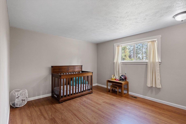 404 E Carriage Ct, Spokane, WA 99218 - bedroom with wood finished floors, a textured ceiling, and a nursery area