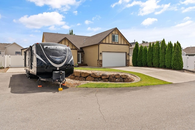 17309 E Baldwin Ave, Spokane Valley, WA 99016 - view of front facade with board and batten siding, a gate, concrete driveway, an attached garage, and stone siding