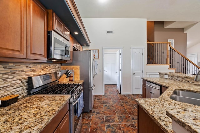 17309 E Baldwin Ave, Spokane Valley, WA 99016 - kitchen featuring stainless steel appliances, backsplash, dark stone finish floors, light stone countertops, and brown cabinetry