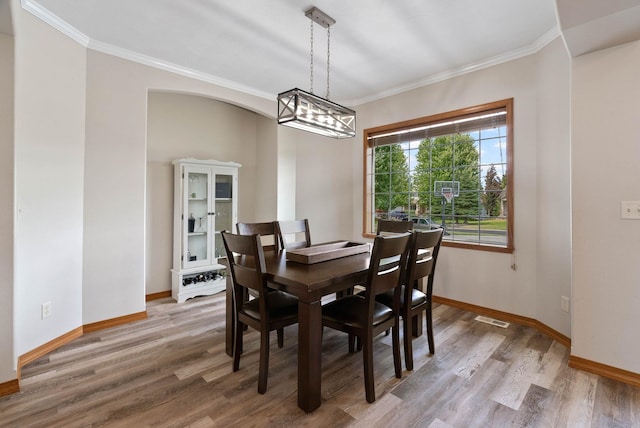 17110 E Daybreak Ln, Spokane Valley, WA 99016 - dining area with light wood-style floors, crown molding, a chandelier, and arched walkways