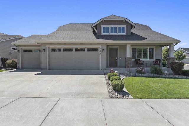 2373 N Colonial Rd, Liberty Lake, WA 99016 - craftsman inspired home featuring an attached garage, concrete driveway, a porch, a front lawn, and a shingled roof