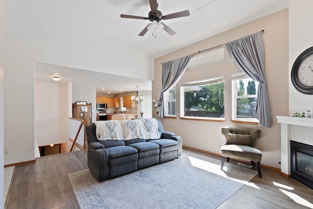 17813 N Lidgerwood St, Colbert, WA 99005 - living area with light wood-style flooring, a glass covered fireplace, a ceiling fan, a chandelier, and vaulted ceiling