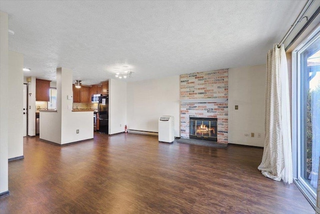 417 Clay St Unit A, Cheney, WA 99004 - unfurnished living room with a textured ceiling, dark wood-type flooring, baseboard heating, and a brick fireplace