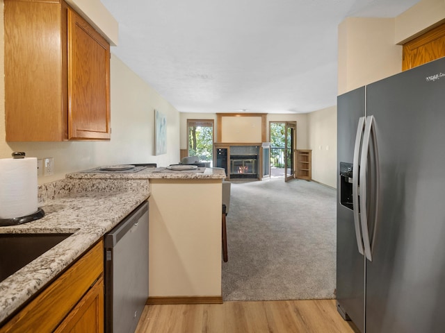 3808 S Alder Dr, Spokane, WA 99223 - kitchen with appliances with stainless steel finishes, open floor plan, a peninsula, brown cabinetry, and light stone countertops