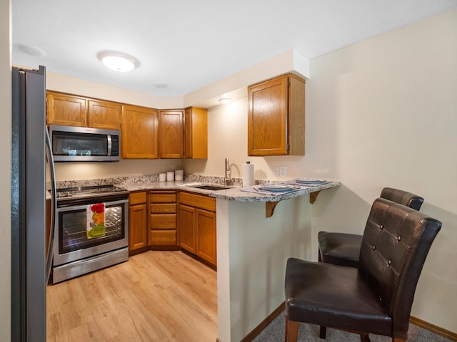 3808 S Alder Dr, Spokane, WA 99223 - kitchen featuring stainless steel appliances, a breakfast bar area, light wood-style floors, brown cabinetry, and a peninsula