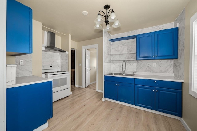 2323 E Rich Ave, Spokane, WA 99207 - kitchen featuring white electric range oven, wall chimney range hood, blue cabinetry, tasteful backsplash, and light wood-style flooring