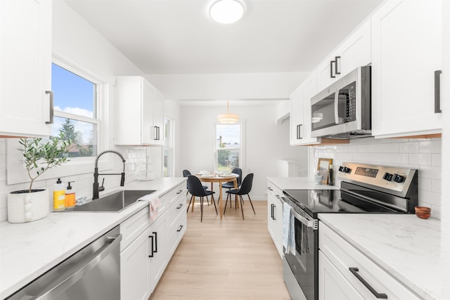 1227 E Providence Ave, Spokane, WA 99207 - kitchen with appliances with stainless steel finishes, white cabinetry, light wood finished floors, and backsplash