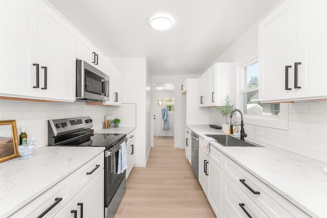 1227 E Providence Ave, Spokane, WA 99207 - kitchen with stainless steel appliances, light stone countertops, white cabinetry, light wood-style flooring, and backsplash