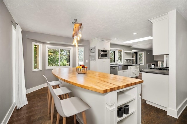 8024 E Elde Dr, Spokane, WA 99212 - kitchen with open shelves, stainless steel appliances, white cabinets, wooden counters, and a center island