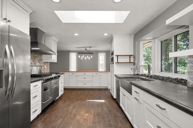 8024 E Elde Dr, Spokane, WA 99212 - kitchen with appliances with stainless steel finishes, a skylight, wall chimney exhaust hood, decorative backsplash, and a textured ceiling