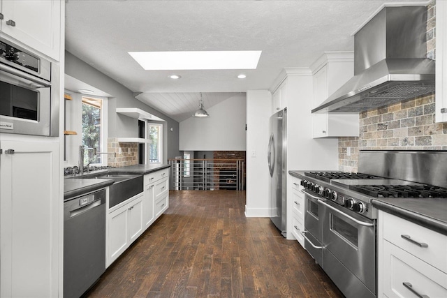 8024 E Elde Dr, Spokane, WA 99212 - kitchen featuring appliances with stainless steel finishes, wall chimney range hood, a skylight, dark countertops, and white cabinets