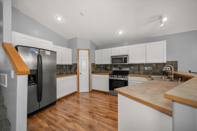 10002 W Richland Rd, Cheney, WA 99004 - kitchen featuring stainless steel appliances, a peninsula, wood finished floors, decorative backsplash, and white cabinetry