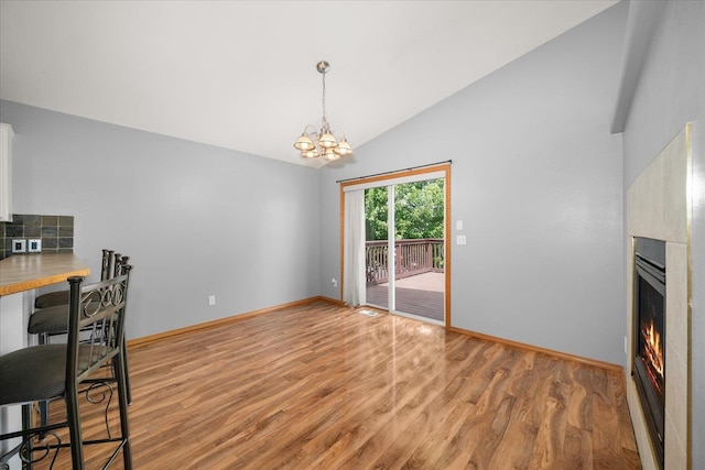 10002 W Richland Rd, Cheney, WA 99004 - unfurnished dining area featuring light wood-style flooring, a chandelier, a warm lit fireplace, and high vaulted ceiling