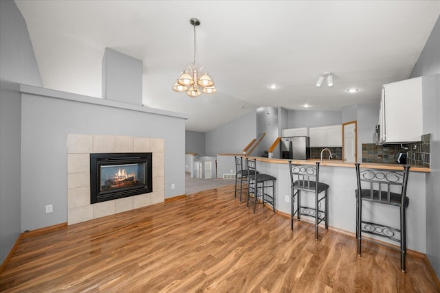 10002 W Richland Rd, Cheney, WA 99004 - kitchen with vaulted ceiling, light wood-style flooring, a kitchen breakfast bar, white cabinets, and stainless steel fridge with ice dispenser