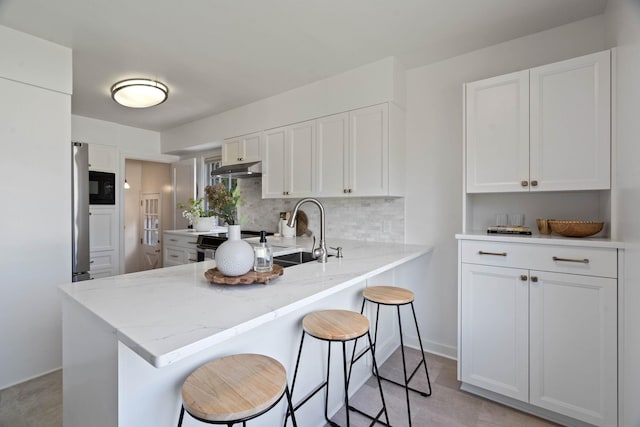 818 W 27th Ave, Spokane, WA 99203 - kitchen featuring white cabinets, a breakfast bar area, a peninsula, backsplash, and black microwave