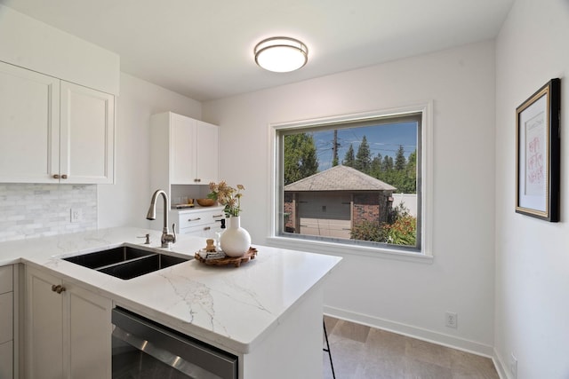 818 W 27th Ave, Spokane, WA 99203 - kitchen with light stone counters, stainless steel dishwasher, white cabinets, a peninsula, and decorative backsplash