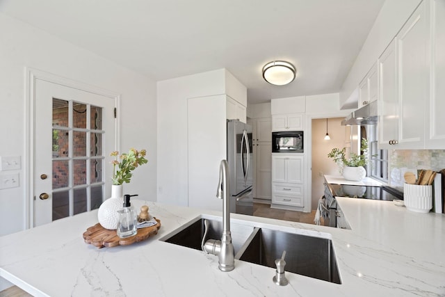 818 W 27th Ave, Spokane, WA 99203 - kitchen with stainless steel appliances, white cabinets, light stone countertops, under cabinet range hood, and healthy amount of natural light