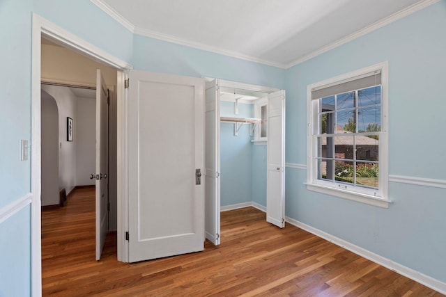 818 W 27th Ave, Spokane, WA 99203 - unfurnished bedroom featuring wood finished floors, crown molding, a closet, and arched walkways