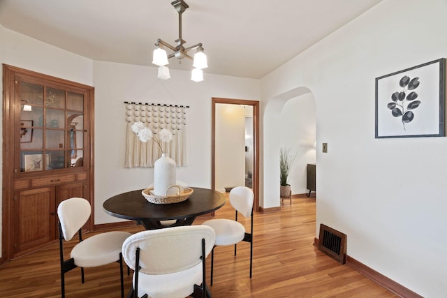 818 W 27th Ave, Spokane, WA 99203 - dining room featuring arched walkways, a chandelier, and light wood-style floors