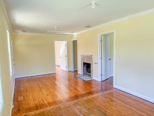 unfurnished living room with hardwood / wood-style floors, crown molding, and a fireplace