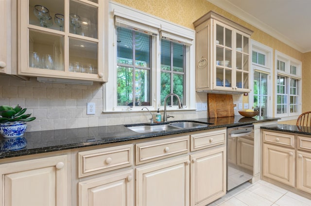 kitchen with ornamental molding, dark stone countertops, sink, and stainless steel dishwasher