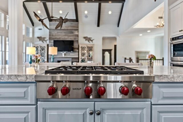 1611 Lighthouse Cir, Greensboro, GA 30642 - kitchen with vaulted ceiling with beams, light stone countertops, appliances with stainless steel finishes, open floor plan, and white cabinets