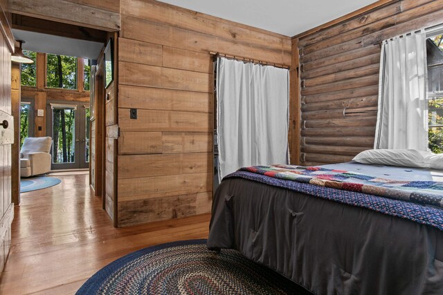 bedroom with log walls and light hardwood / wood-style floors