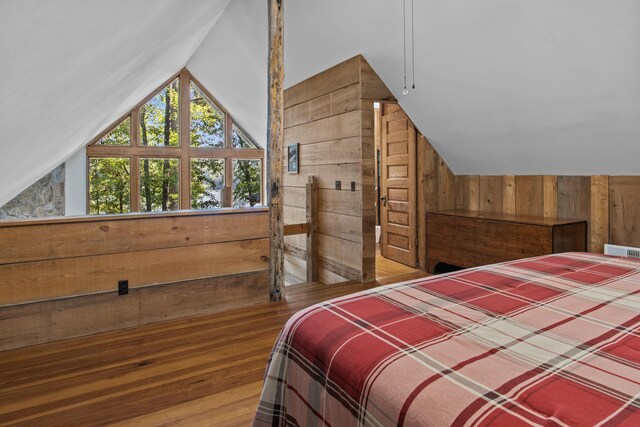 bedroom with lofted ceiling, hardwood / wood-style floors, and wood walls