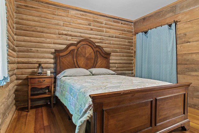 bedroom featuring hardwood / wood-style floors and log walls