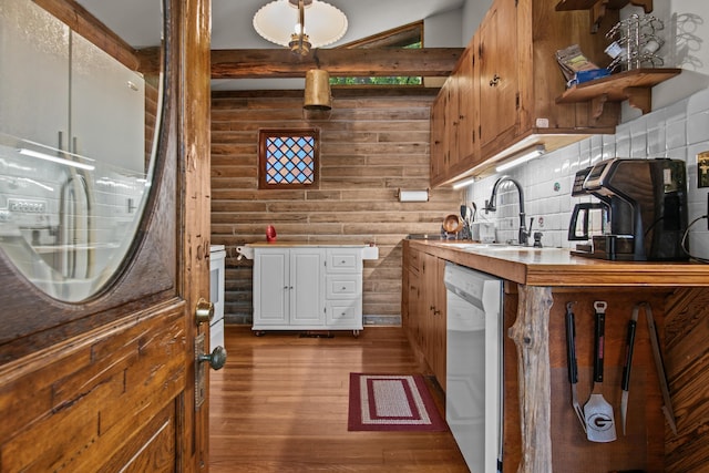 kitchen featuring sink, dishwasher, log walls, hardwood / wood-style floors, and decorative backsplash