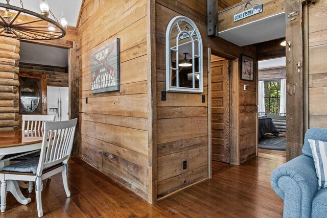 interior space featuring dark wood-type flooring, a notable chandelier, and wooden walls