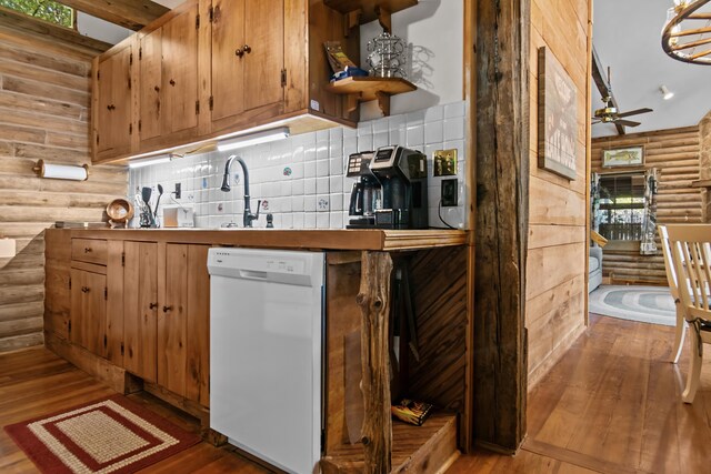 kitchen featuring wood-type flooring, rustic walls, white dishwasher, and decorative backsplash