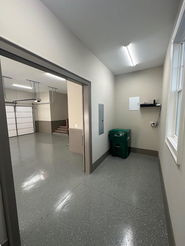 interior space with electric panel, baseboards, and speckled floor