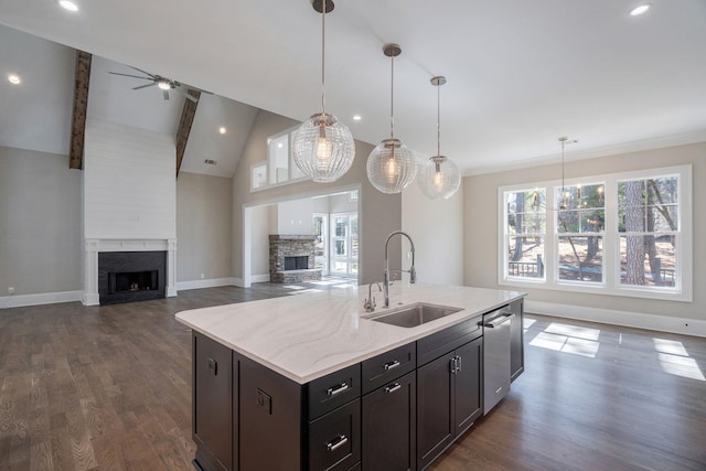 kitchen featuring dishwasher, open floor plan, dark wood-type flooring, a fireplace, and a sink