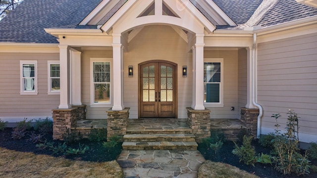 entrance to property featuring french doors, a porch, and a shingled roof