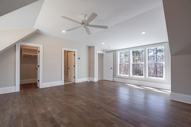 interior space featuring lofted ceiling, a spacious closet, a ceiling fan, wood finished floors, and baseboards