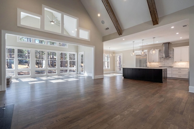 unfurnished living room featuring baseboards, dark wood-type flooring, ceiling fan with notable chandelier, beam ceiling, and recessed lighting