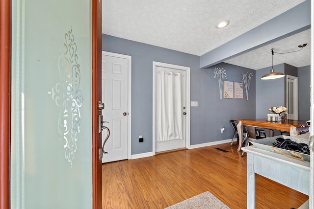 kitchen featuring visible vents, pendant lighting, a textured ceiling, light wood finished floors, and baseboards