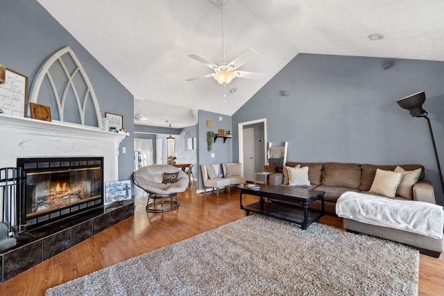 living area with a glass covered fireplace, high vaulted ceiling, a ceiling fan, and wood finished floors