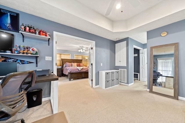 office space featuring light carpet, visible vents, baseboards, and a ceiling fan