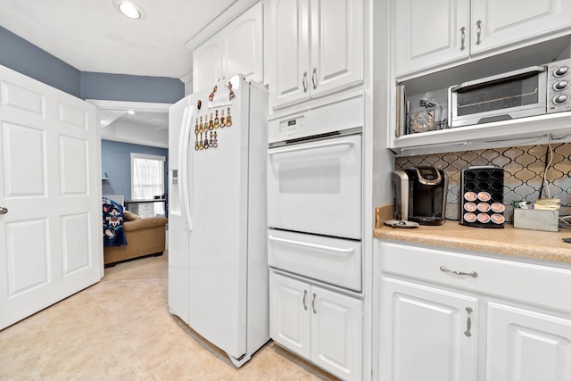 kitchen featuring white appliances, light countertops, white cabinetry, a warming drawer, and tasteful backsplash