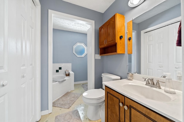 bathroom with toilet, vanity, a garden tub, a closet, and a textured ceiling