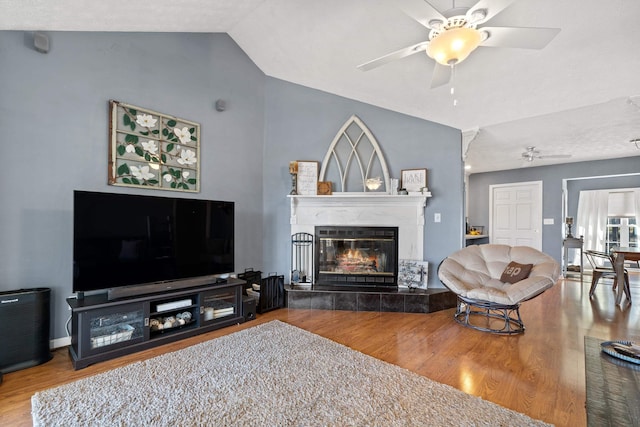 living area with a fireplace, lofted ceiling, wood finished floors, and ceiling fan