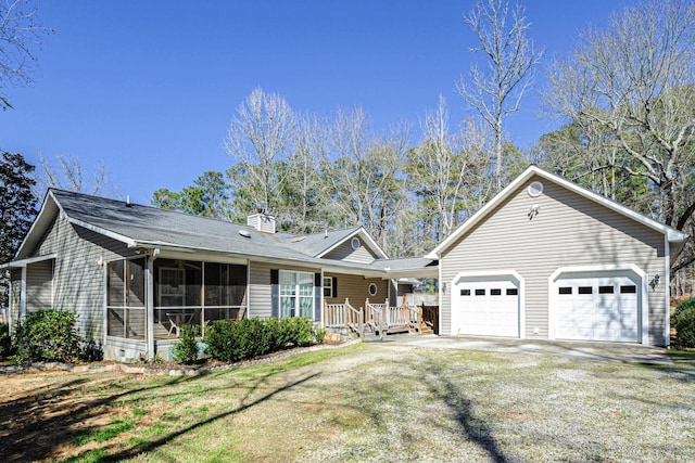 single story home with a front yard, a chimney, a garage, a sunroom, and driveway