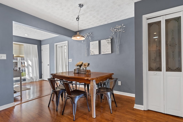 dining space with wood finished floors, baseboards, and a textured ceiling