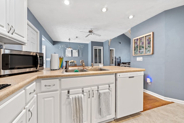 kitchen featuring a peninsula, white dishwasher, ceiling fan, a sink, and stainless steel microwave