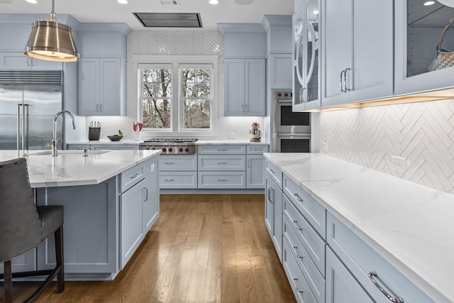 kitchen featuring sink, gray cabinetry, pendant lighting, stainless steel appliances, and light stone countertops