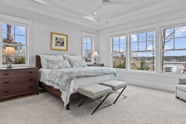 bedroom with crown molding, light carpet, ceiling fan, and a tray ceiling